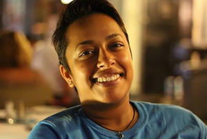 Picture of a smiling South Asian American woman in a blue t shirt, who is the founder and CEO of Timberdog, an innovative company that sells travel pet items