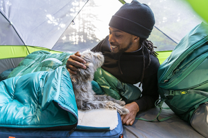 Man lovingly interacting with his dog before they both go to sleep in their respective sleeping bags in his tent, dog beds for large dogs, dog bed for small dogs, cave dog bed, cave pet bed, dog cave bed, pet cave bed