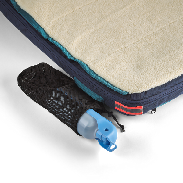 Black mesh pocket emerging from the side of the blue dog bed, holding a 32 oz water bottle, dog beds for large dogs, best dog beds for small dogs