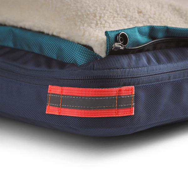 Close up showing detail of the orange corner reflective accent and loop on small blue dog bed for travel, home, office, or on the road, dog beds for large dogs, best dog beds for small dogs